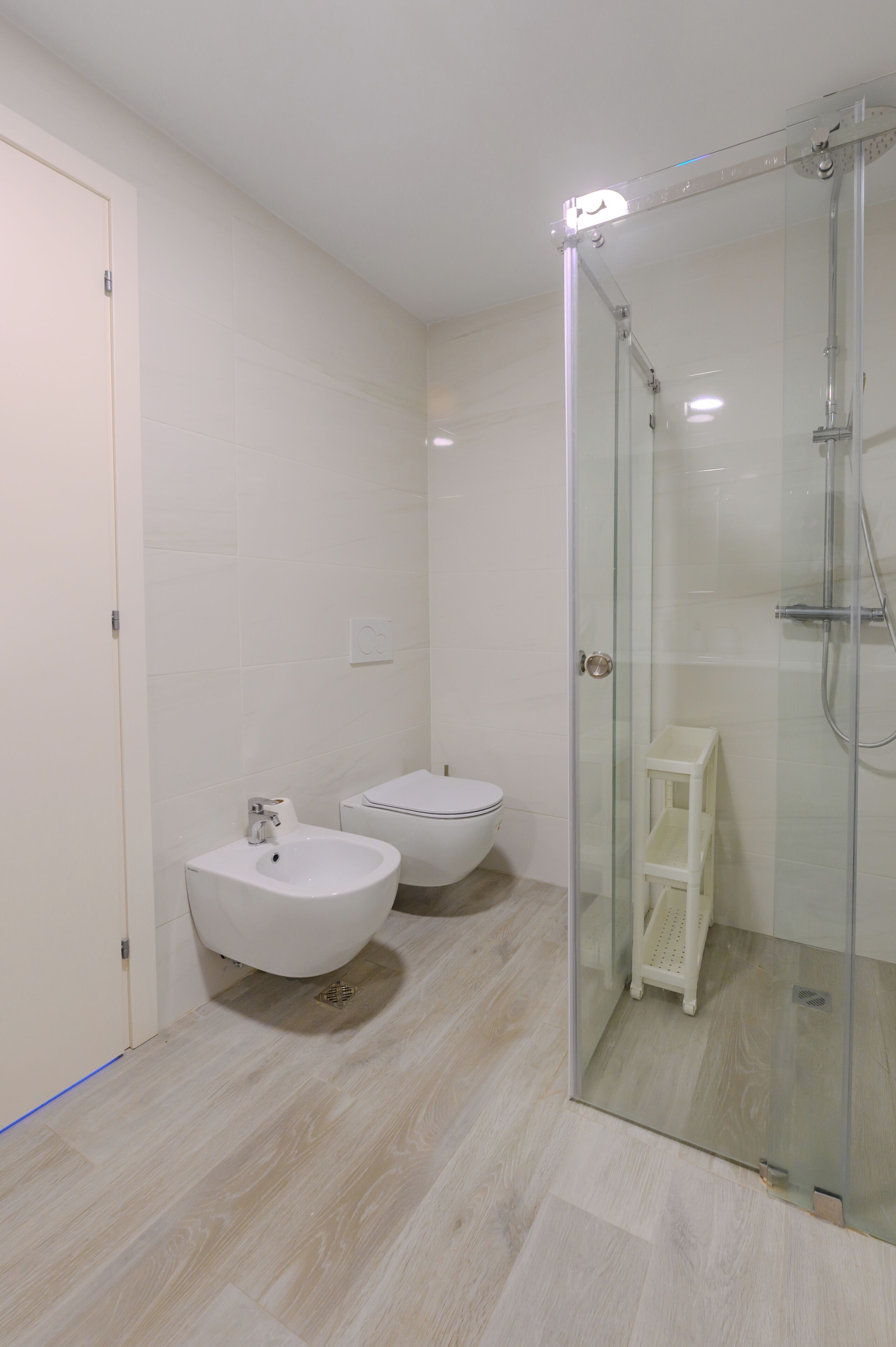 A modern bathroom with a glass-enclosed shower, a bidet, and a toilet.