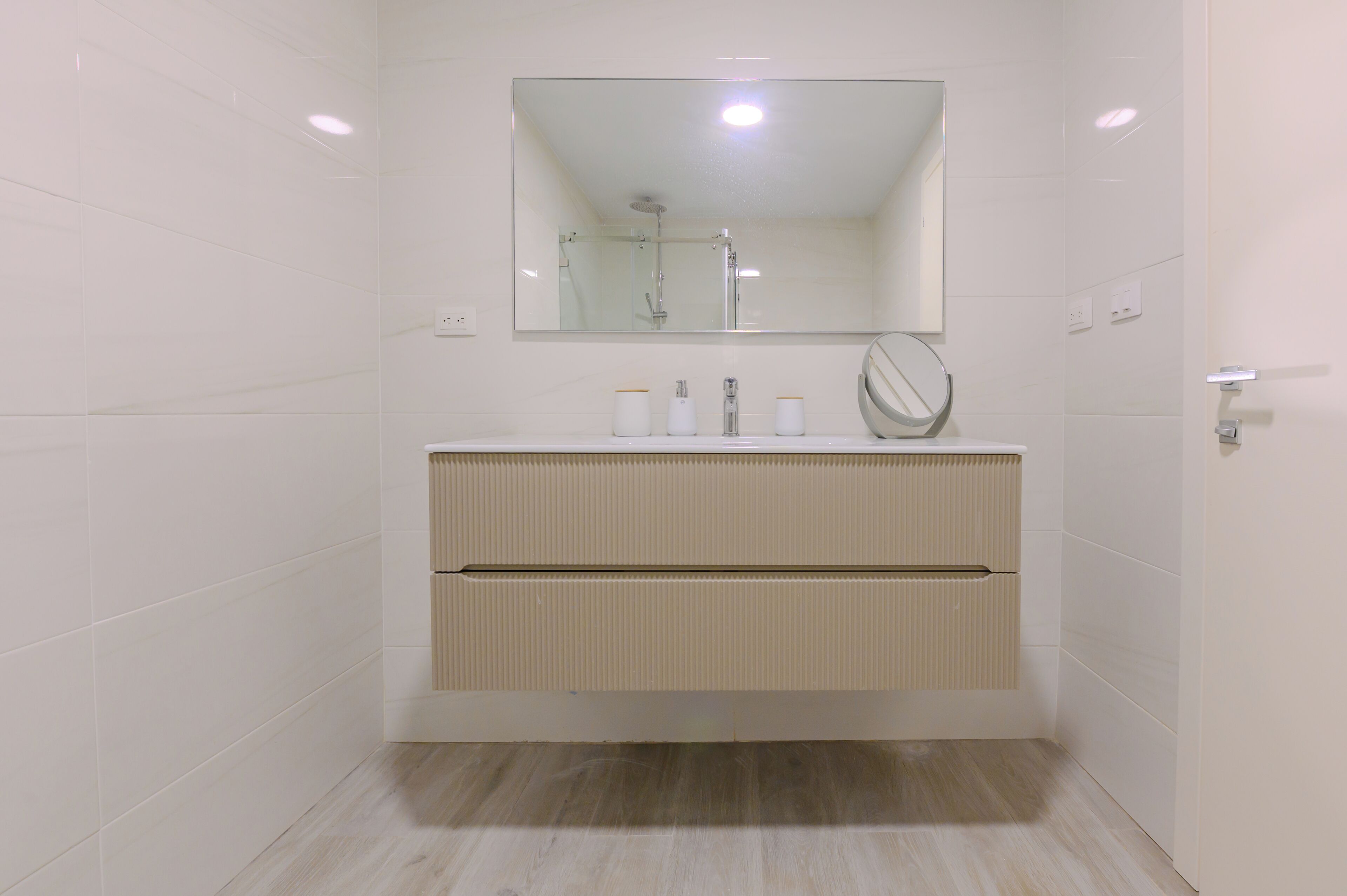 Une salle de bain avec un miroir, un lavabo et une douche.