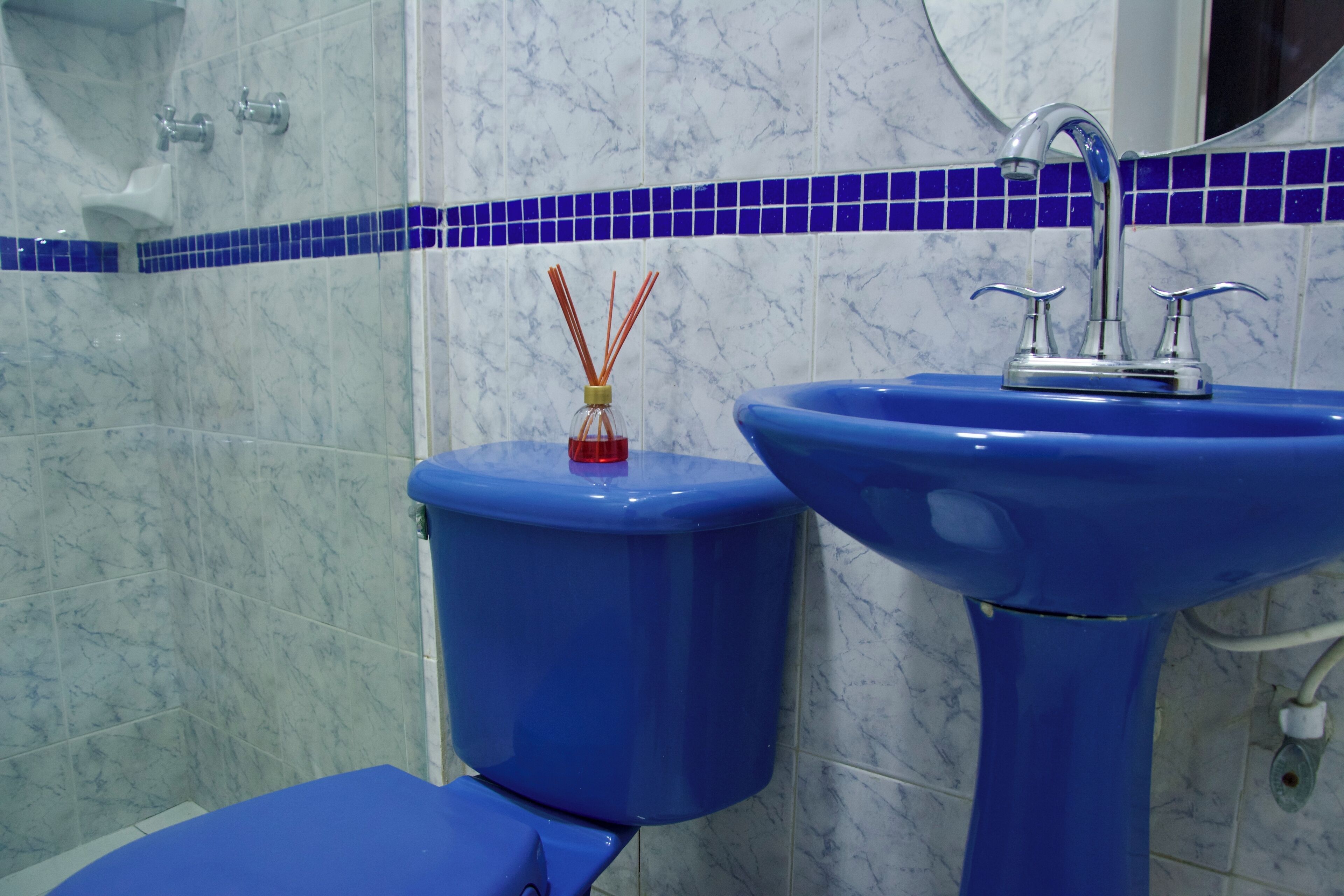 Ein Badezimmer mit blauer Toilette, blauem Waschbecken und einer blauen Duschkabine.