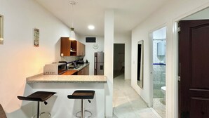 Una cocina moderna con una isla central, dos taburetes de bar, microondas y refrigerador.