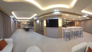A modern living room with a dining area, kitchen, and bar/lounge area. - Plaza Court Hotel (Georgetown)