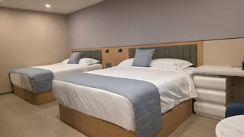 A hotel room with two single beds, a desk, and a chair.