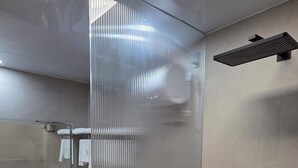 A modern bathroom with a glass partition, a large mirror, a sink, and a shower area. - Plaza Court Hotel (Georgetown)