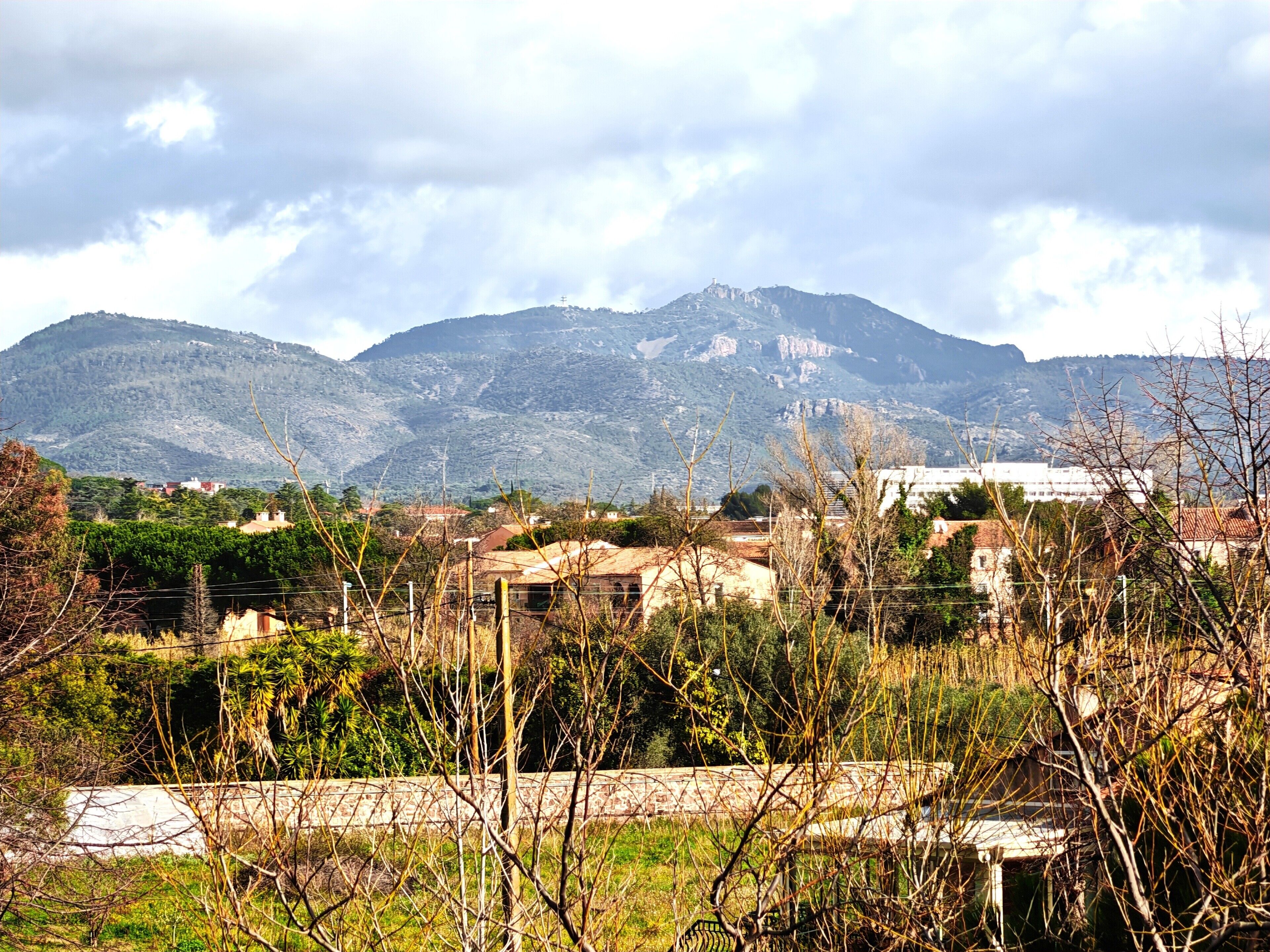 Un paysage montagneux avec des bâtiments au premier plan et une église sur une colline à l’arrière-plan.