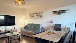 A modern living room with a flat-screen TV, a sofa, a dining table with chairs, and a small kitchen area with a microwave and a coffee maker. - View of the Esterel massif from the Avant-Scene, Frejus on foot (Fréjus)