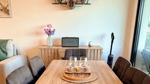 A wooden dining table with four chairs, a tray with glasses and snacks, a small table with a vase of flowers, a clock, and a speaker on a wooden cabinet. - View of the Esterel massif from the Avant-Scene, Frejus on foot (Fréjus)