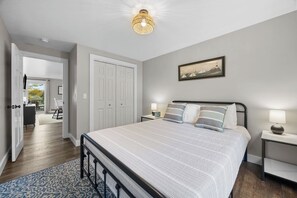 Ein Schlafzimmer mit einem großen Bett, Nachttischen, einer Chandelieber, einer Tür und einem Gemälde an der Wand.