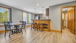 Una cocina con comedor, taburetes de madera y vistas al exterior.
