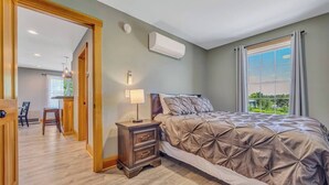 Un dormitorio con cama, mesita de noche, lámpara y aire acondicionado.