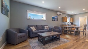 Un salon comprenant un canapé, des fauteuils, une table basse et un coin repas avec une table et des chaises.