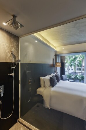 Una habitación de hotel moderna con una cama grande, zona de ducha y vistas al exterior.