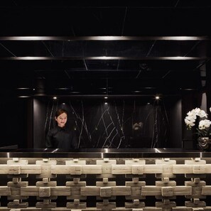 A reception area with a marble wall, a reception desk, and a patterned floor. - Kiri Hotel Chiang Mai (Chiang Mai)