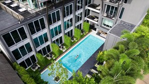 A modern building with a rooftop pool, large windows, and outdoor seating areas. - Kiri Hotel Chiang Mai (Chiang Mai)