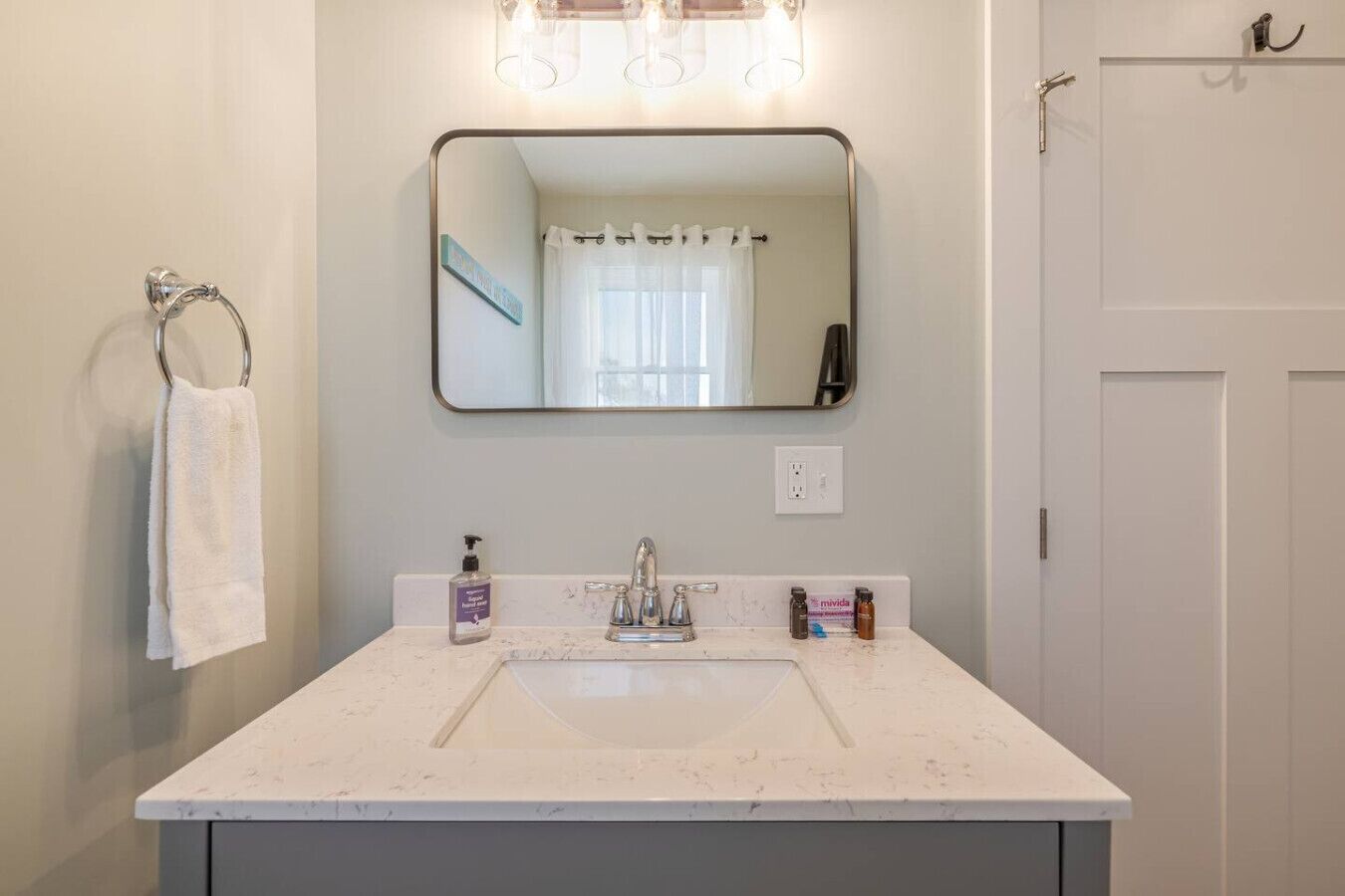 A bathroom with a white sink, a mirror, and a towel rack.