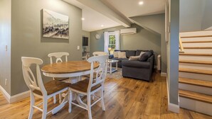 En moderne stue med spisebord, stole, sofa og trappe.