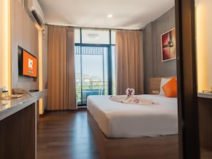 Habitación de hotel con una cama, un escritorio con teléfono, un televisor y vistas al exterior.