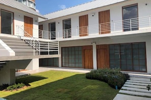 A modern building with a flat roof, large windows, and a small courtyard with a lawn and steps. - Kyoto Great Hotel (Chiang Mai)