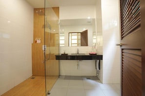 A modern bathroom with a glass-enclosed shower, a wooden door, a black sink, and a mirror. - Kyoto Great Hotel (Chiang Mai)