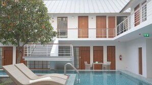 A modern indoor swimming pool with a lounge chair, wooden doors, and a staircase. - Four O'clock Hotel (Chiang Mai)