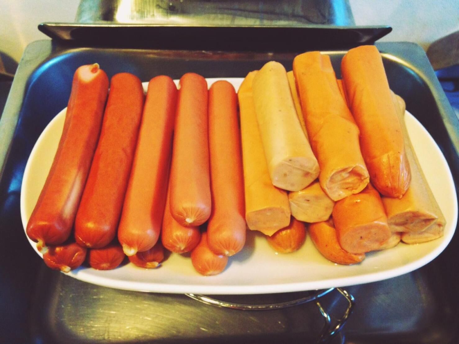 Une assiette blanche sur laquelle sont disposés des saucisses chaudes.
