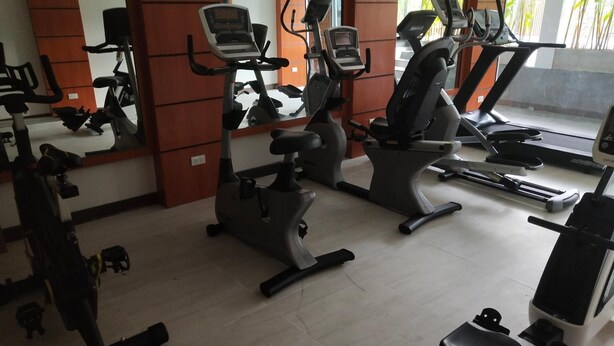 A gym with various exercise equipment including treadmills, stationary bikes, and elliptical machines. - Hotel De Wualai-sha Extra Plus (Chiang Mai)