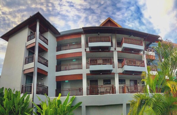 A multi-story hotel with balconies, a curved roof, and a white facade. - Hotel De Sripoom -sha Extra Plus (Chiang Mai)