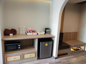 A kitchenette with a microwave, refrigerator, and storage drawers. There are towels, a basket of snacks, and a water bottle on the counter. - Hotel De Sripoom -sha Extra Plus (Chiang Mai)