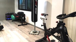 A gym with a stationary bike, a punching bag, and exercise equipment. - Hotel De Sripoom -sha Extra Plus (Chiang Mai)