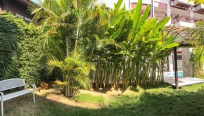 A garden with palm trees, a bench, and a pool area. - Hotel De Sripoom Sha Extra Plus (Chiang Mai)