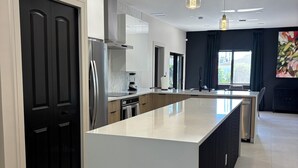 Cocina moderna con una isla central, muebles negros y un amplio ventanal que proporciona luz natural.