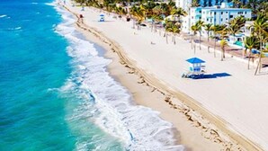 Una playa con una hilera de edificios, palmeras y una torre de salvavidas.