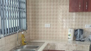 A kitchen with a gas stove, two sinks, wooden cabinets, and patterned wallpaper.