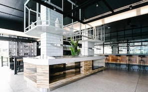 A modern kitchen with a central island, bar stools, and a large window providing natural light. - Book Design Hotel Sha Extra Plus (Chiang Mai)