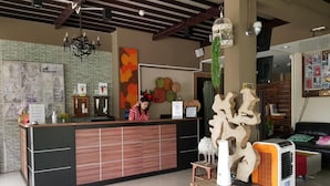 Un comptoir d’accueil avec un réceptionniste, une grande peinture abstraite et une sculpture en bois originale.