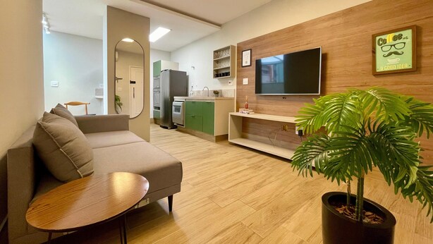 A modern living room with a sofa, a coffee table, a TV, and a potted plant. - Beachfront apartment, two suites, Post 9 - Ipanema (Rio de Janeiro)