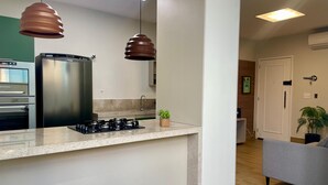 A modern kitchen with stainless steel appliances, a granite countertop, pendant lighting, and a small potted plant. - Beachfront apartment, two suites, Post 9 - Ipanema (Rio de Janeiro)