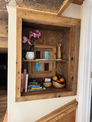 Ein Holzregal mit Büchern, einer Blumenvase und einer Schüssel Orangen.