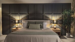 A bedroom with a large bed, two bedside lamps, a potted plant, and a dark headboard. - Mountain Modern Pine Mountain Lake Retreat / Near Yosemite + Lake Access (Groveland)
