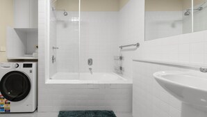 Ein modernes Badezimmer mit Waschmaschine, Badewanne und Waschbecken.