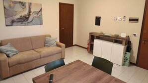 Una sala de estar con un sofá color beige, una mesa de centro de madera y un cuadro en la pared.