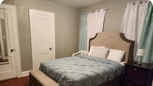 Ein Schlafzimmer mit Bett, Bank, Nachttisch und einer Tür.