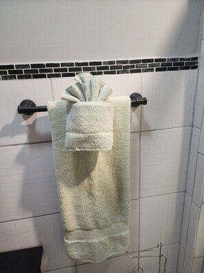 A bathroom with a white tiled wall, a black and white tiled backsplash, and a towel rack with a folded towel.