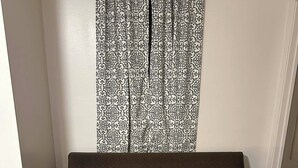 A brown sofa with a green and white blanket, positioned in front of a patterned curtain. - Private Guest Suite in Historic Home (Sioux Falls)
