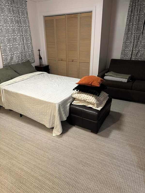 Une chambre à coucher comprenant un lit, une table de chevet, une armoire et un canapé.