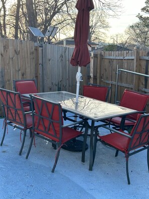 A patio with a table and chairs, a solar panel, and a wooden fence. - Mara Retreat : Unit A: Fire Pit-Grill-Groups-Patio-Games-Ping Pong Table (Birmingham)