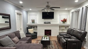 A living room with a fireplace, a sofa, a recliner, and a coffee table. - Mara Retreat : Unit A: Fire Pit-Grill-Groups-Patio-Games-Ping Pong Table (Birmingham)