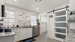 A modern kitchen with white cabinets, granite countertops, and a built-in dishwasher. - Mara Retreat : Unit A: Fire Pit-Grill-Groups-Patio-Games-Ping Pong Table (Birmingham)