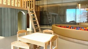 A modern interior with a wooden play area, including a table and chairs, and a ball pit. - The Park Toreo 407. Modern apartment, private parking, Wi-Fi, great city views. (Tijuana)