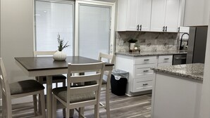 A modern kitchen with white cabinets, a marble backsplash, and a stainless steel refrigerator. - Newly remodeled home on a quiet street with a large yard. (Salt Lake City)
