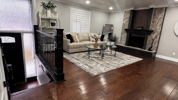 A spacious living room with hardwood flooring, a sofa, a coffee table, and a fireplace. - Newly remodeled home on a quiet street with a large yard. (Salt Lake City)